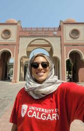 A woman in a hijab takes a selfie in front of an ornate building
