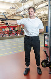 A man wearing athletic wear workouts his shoulder