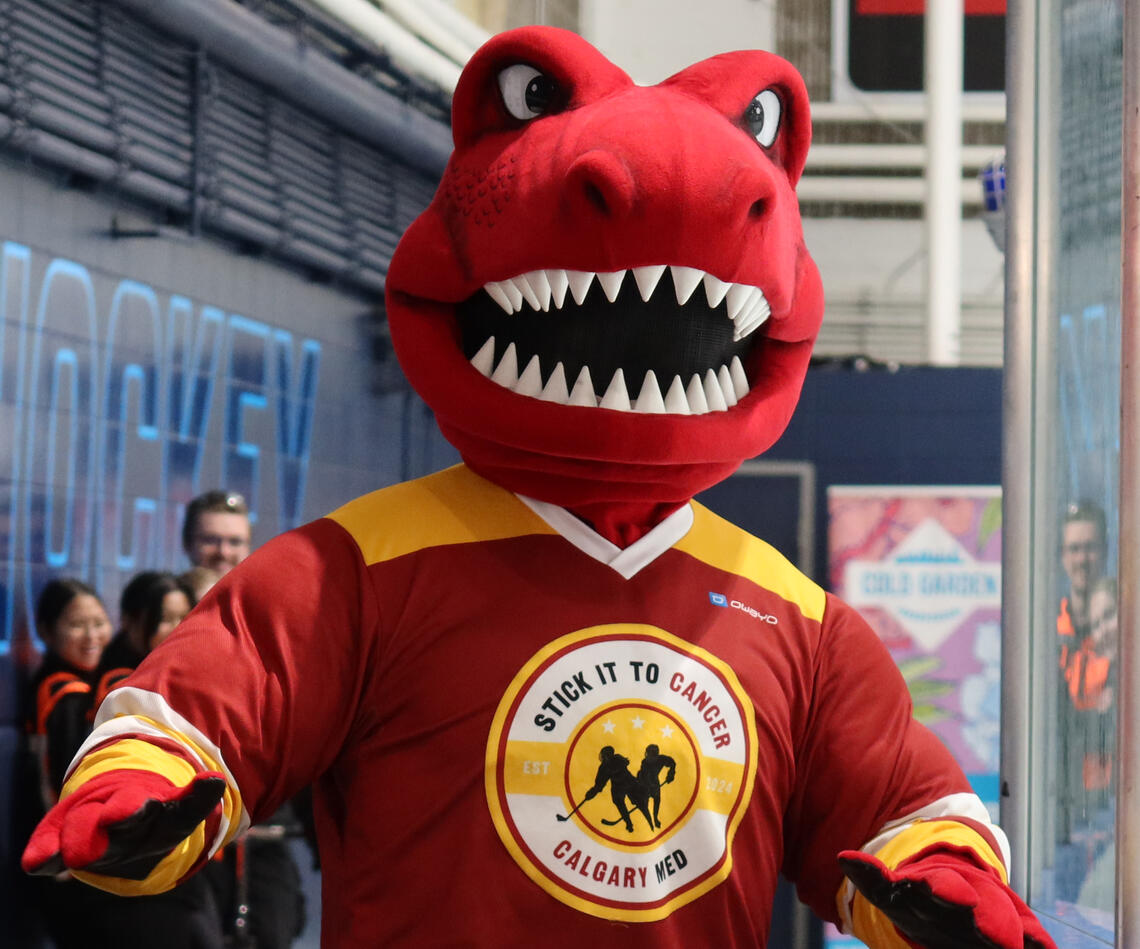 A red dinosaur mascot wears a hockey jersey