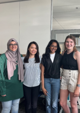 Four studnets smiling in an office on campus